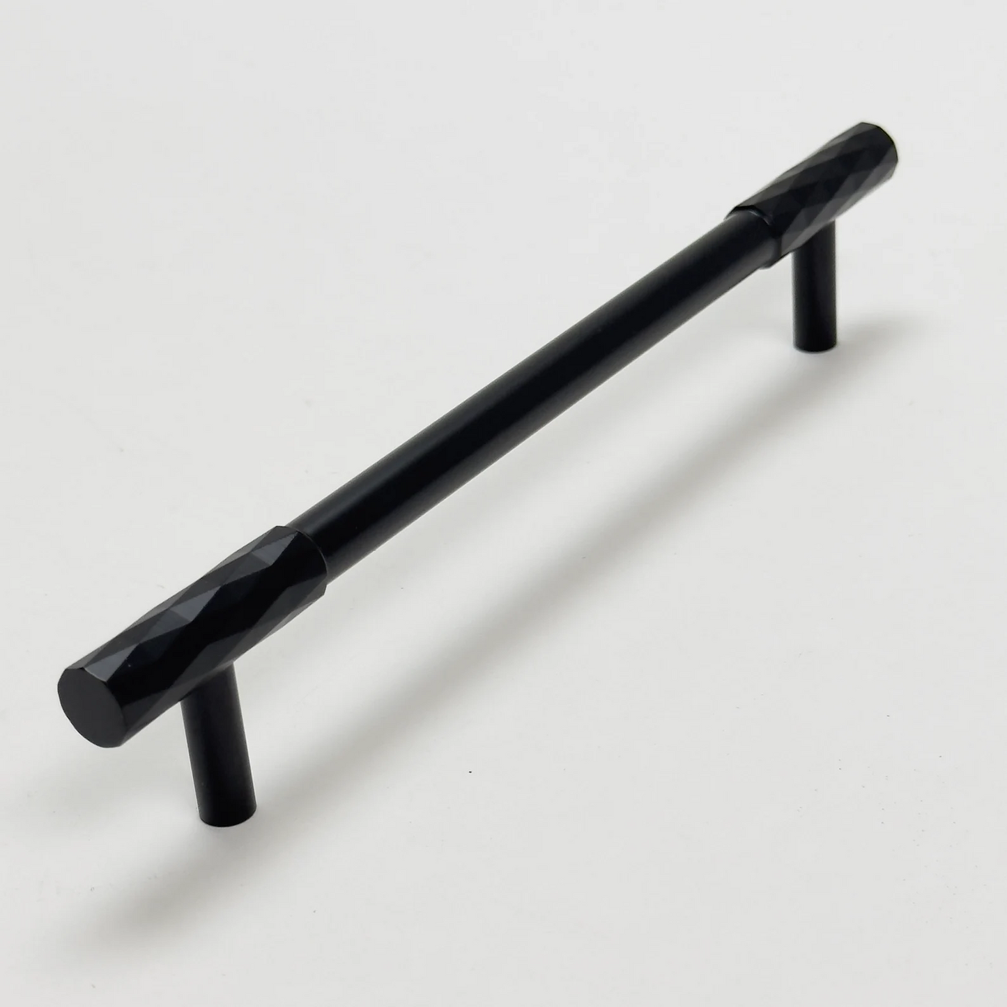 Black faceted brass cabinet pull and round knob, shown from one angle with its shape and finish visible
