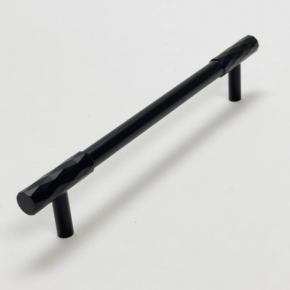 Black faceted brass cabinet pull and round knob, shown from one angle with its shape and finish visible