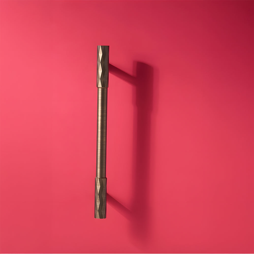 Bronze faceted brass cabinet pull and round knob, shown clearly on a clean neutral background