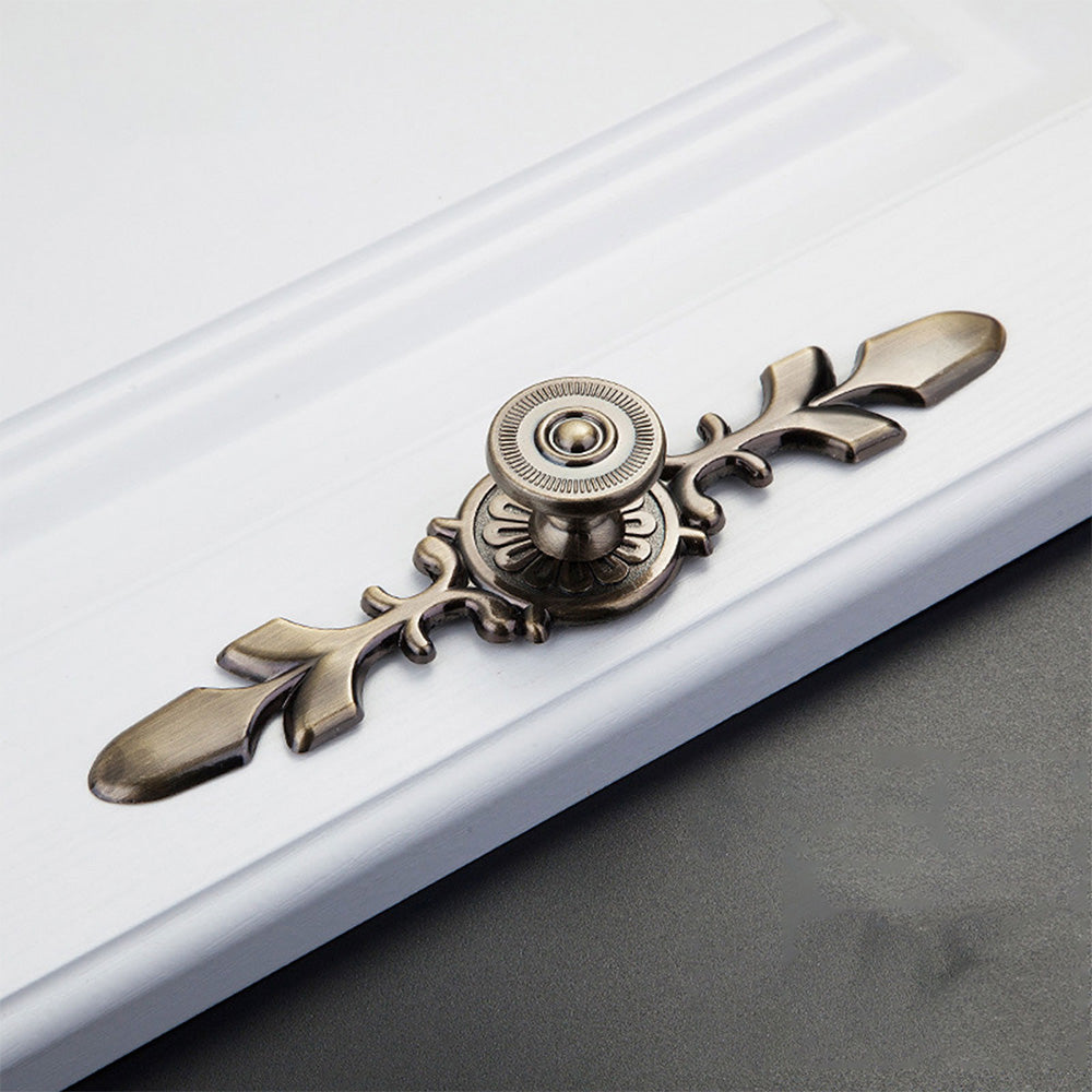 Bronze round cabinet knob with ornate floral backplate, shown at close range on a clean neutral background