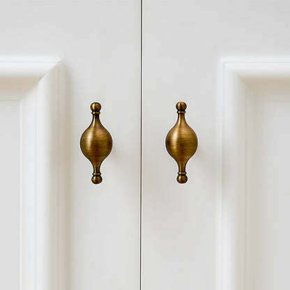 French retro turned brass cabinet pull and spindle knob, presented for reference installed on cabinetry in context