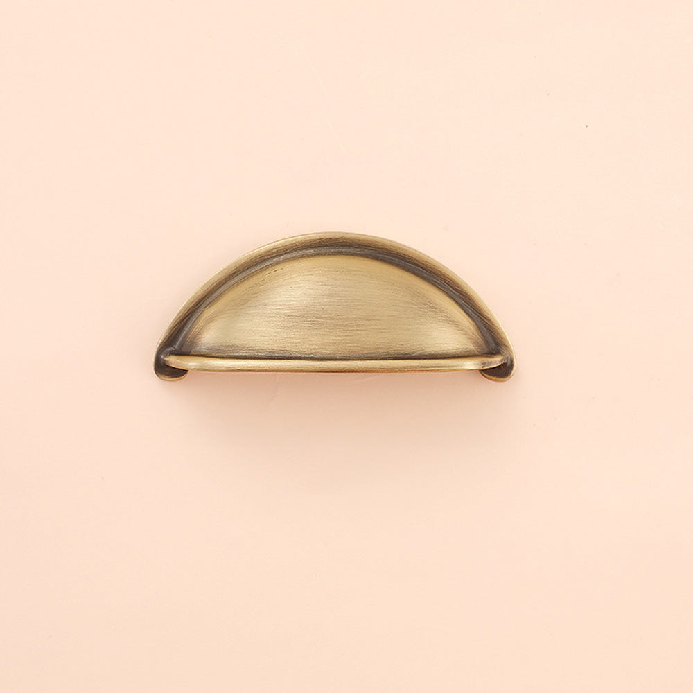 Half-round brass cabinet cup pull, shown in a focused view on a clean neutral background