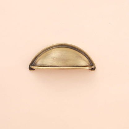 Half-round brass cabinet cup pull, shown in a focused view on a clean neutral background