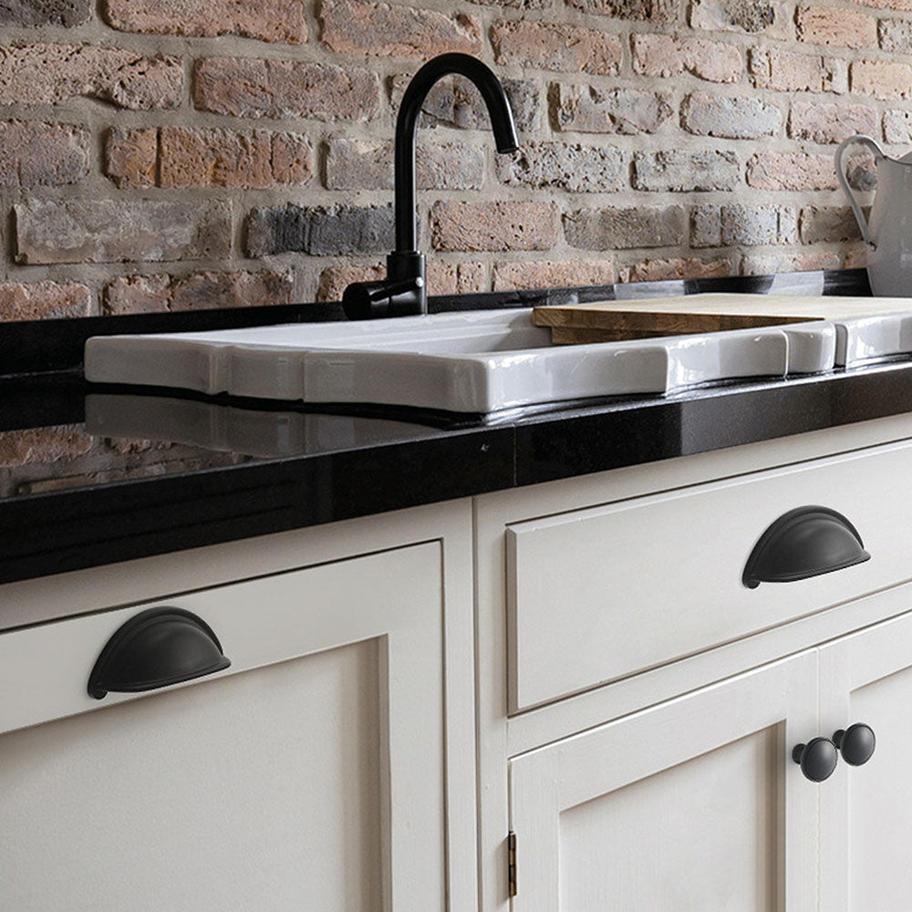 Black half-round brass cabinet cup pull, shown at close range installed on cabinetry in context