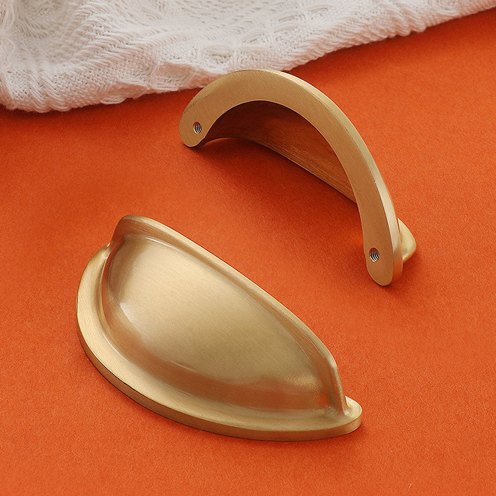 Half-round brass cabinet cup pull, shown from one angle with its construction and finish visible