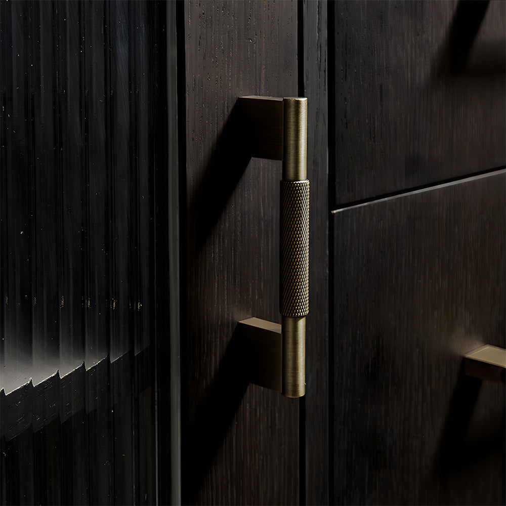 Knurled brass cabinet pull with rectangular mounts and knob, shown at close range installed on cabinetry in context