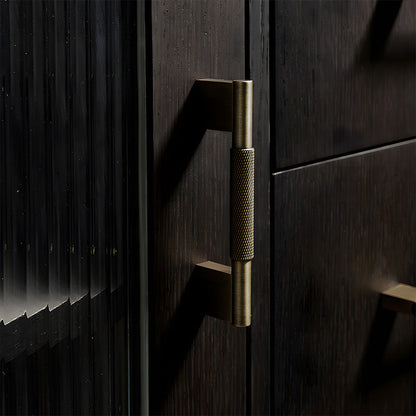 Knurled brass cabinet pull with rectangular mounts and knob, shown at close range installed on cabinetry in context