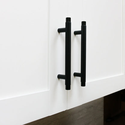 Black knurled T-bar cabinet pull, presented for reference in an installed cabinet close-up