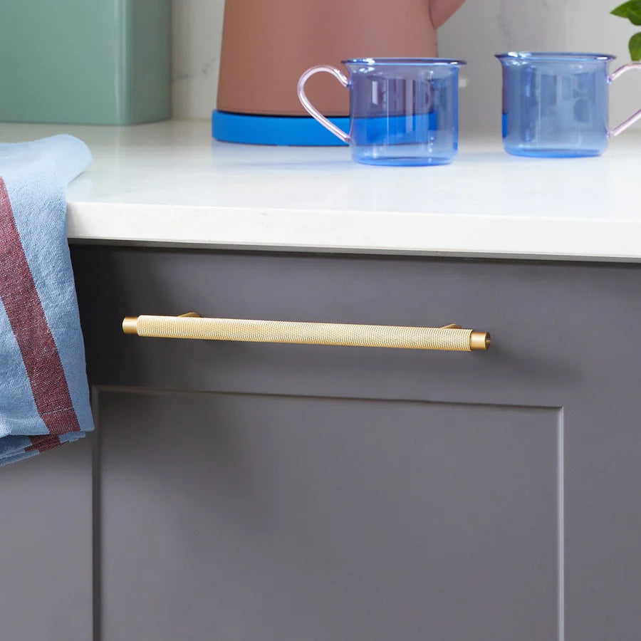 Gold knurled T-bar cabinet pull, shown clearly installed on cabinetry in context
