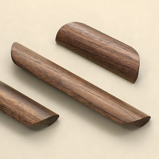Low-profile walnut cabinet pull in black walnut, grouped on a light surface to compare lengths and profiles