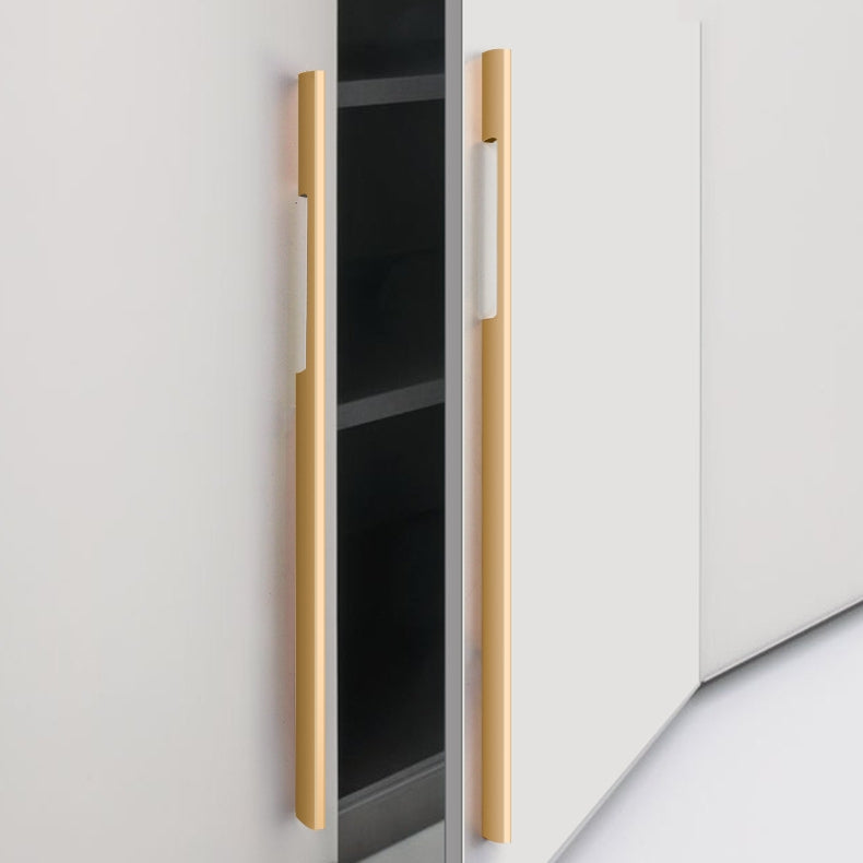 Gold slim rectangular aluminum cabinet pull, shown from one angle in an installed cabinet close-up