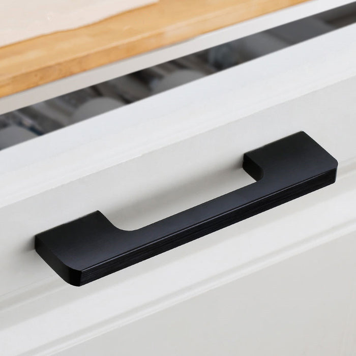 Black slim rectangular aluminum cabinet pull, pictured in one view in an installed cabinet close-up