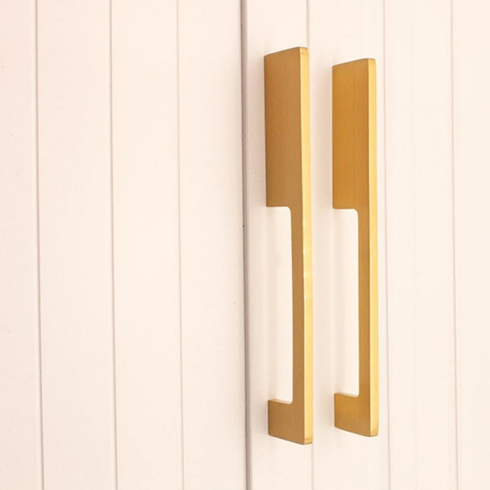 Gold slim rectangular aluminum cabinet pull, presented for reference in an installed cabinet close-up
