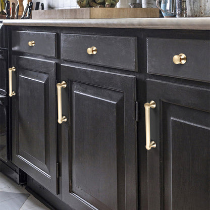 Traditional cabinet pull with flared mounts and knob, shown from one angle installed on cabinetry in context