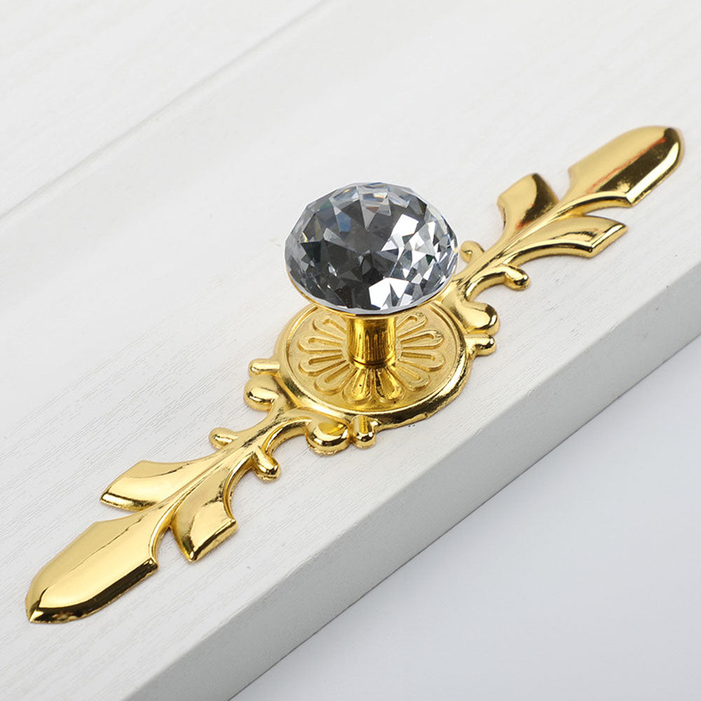 Faceted crystal cabinet knob with ornate leaf backplate, presented for reference on a clean neutral background