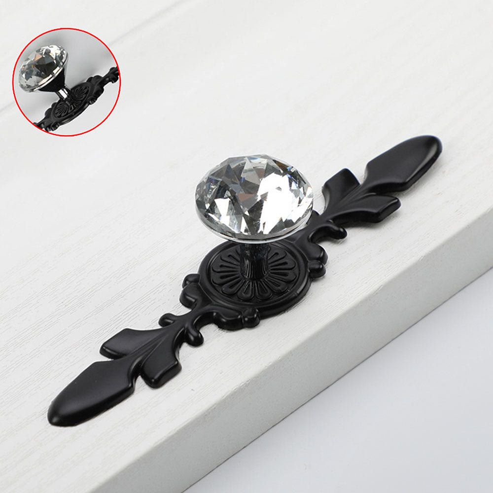Faceted crystal cabinet knob with ornate leaf backplate, shown at close range with its construction and finish visible