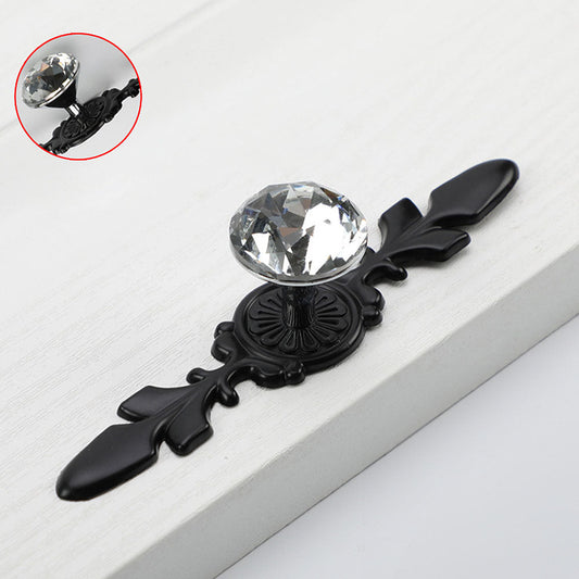 Faceted crystal cabinet knob with ornate leaf backplate, shown at close range with its construction and finish visible
