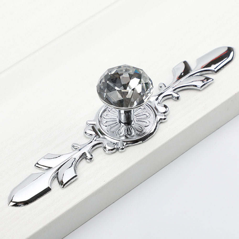 Faceted crystal cabinet knob with ornate leaf backplate, shown clearly on a clean neutral background