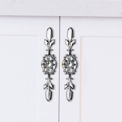 Faceted crystal cabinet knob with ornate leaf backplate, shown clearly in an installed cabinet close-up