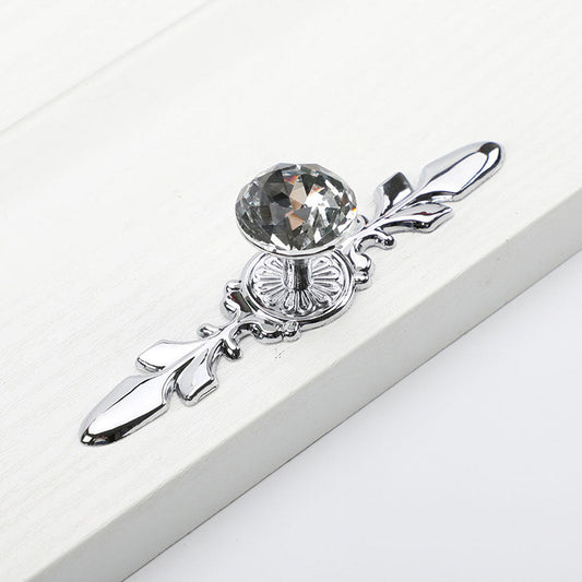 Faceted crystal cabinet knob with ornate leaf backplate, shown from one angle on a clean neutral background