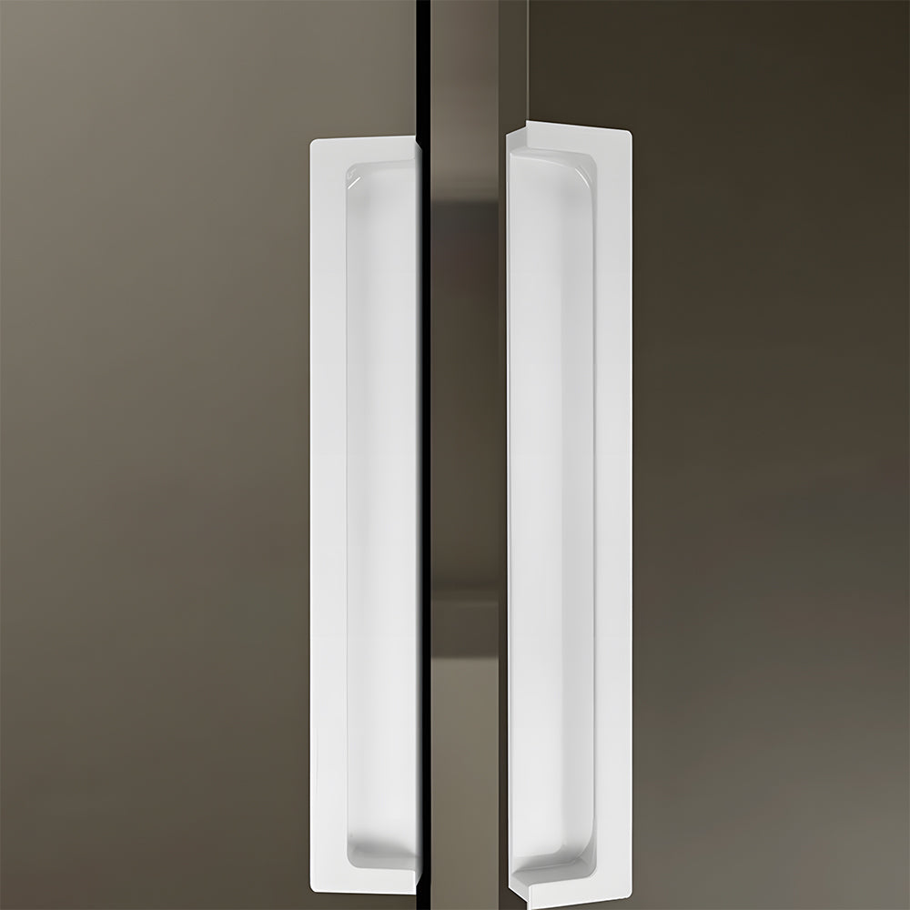 White concealed slotted cabinet pull, shown from one angle in an installed cabinet close-up