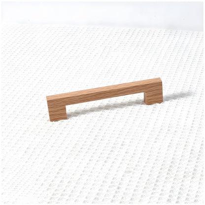 Square wood cabinet pull in oak with 128 mm centers, shown alone at an angle on a light background
