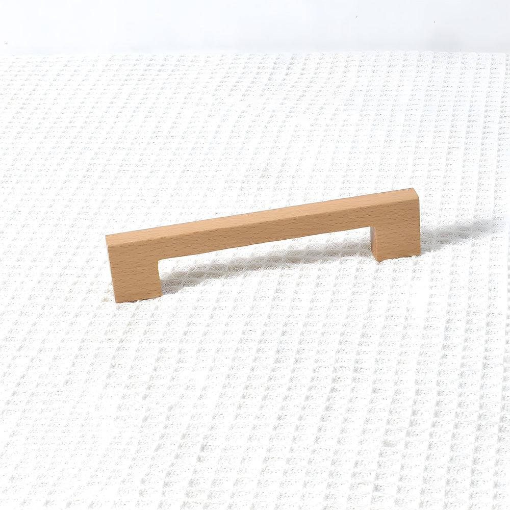 Square wood cabinet pull in beech with 128 mm centers, shown from a close side angle against a plain surface