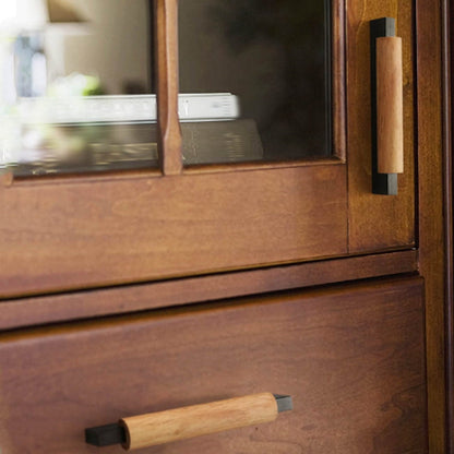 Wood cabinet pull with black or silver metal ends, installed on paired cabinet doors in a close view