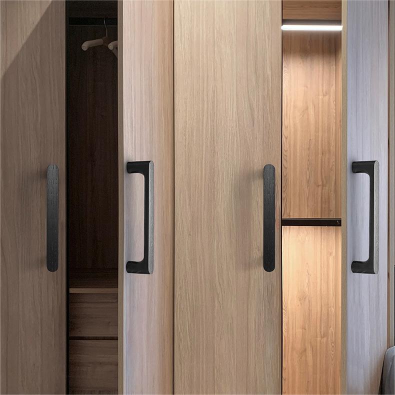 Rounded wood cabinet pull in black, installed vertically on paired wardrobe doors