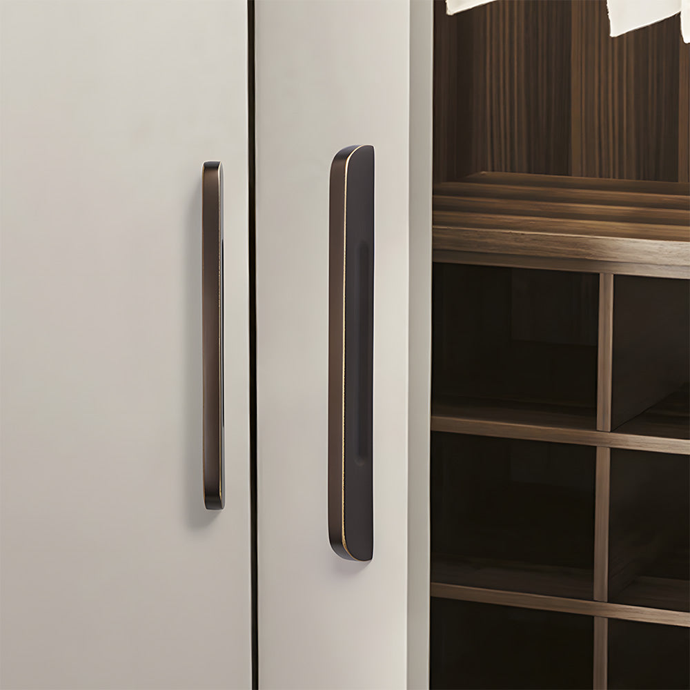 Recessed brass drawer pull with matching cabinet knob, shown at close range installed on cabinetry in context