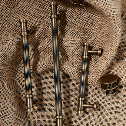 Ribbed bronze cabinet pull and round knob, shown from one angle with related hardware in one display