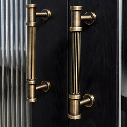 Ribbed bronze cabinet pull and round knob, shown clearly in an installed cabinet close-up