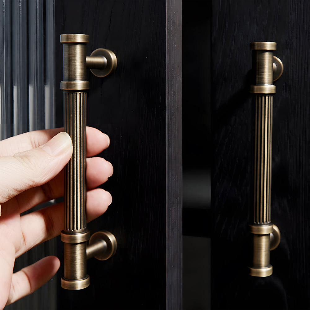 Ribbed bronze cabinet pull and round knob, shown clearly while held or operated by hand