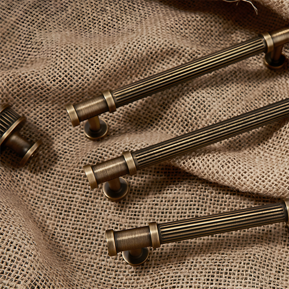 Ribbed bronze cabinet pull and round knob, presented for reference with related hardware in one display