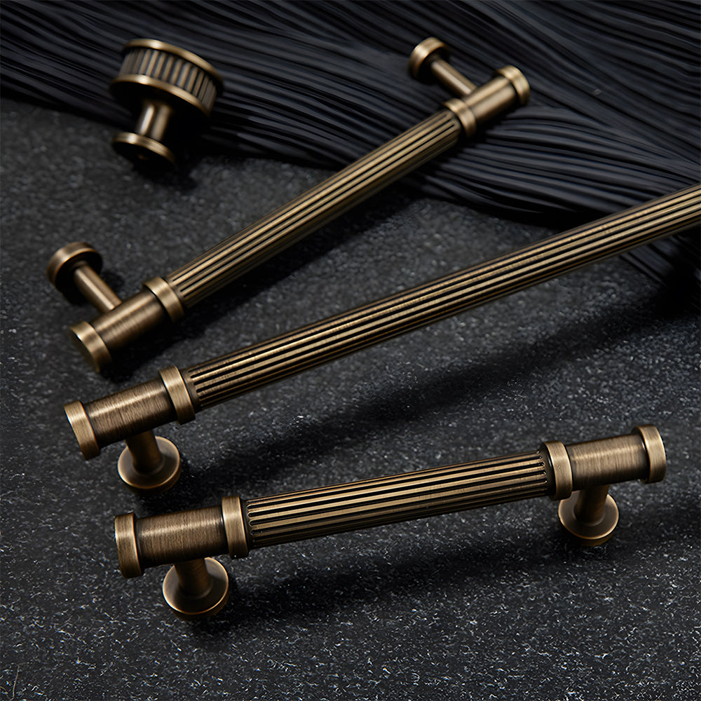 Ribbed bronze cabinet pull and round knob, shown at close range with related hardware in one display