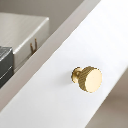 Gold ribbed bar cabinet pull and round knob, pictured in one view in an installed cabinet close-up