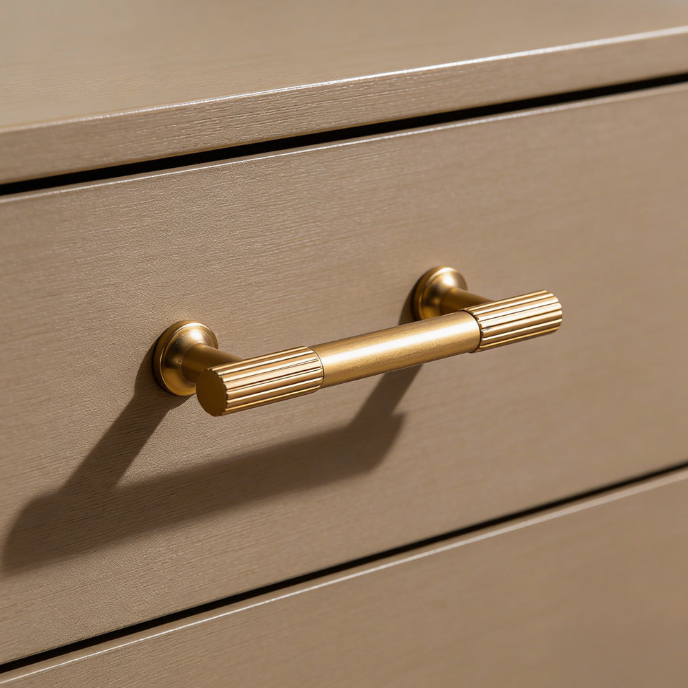 Matte gold ribbed bar cabinet pull and round knob, shown in a focused view in an installed cabinet close-up
