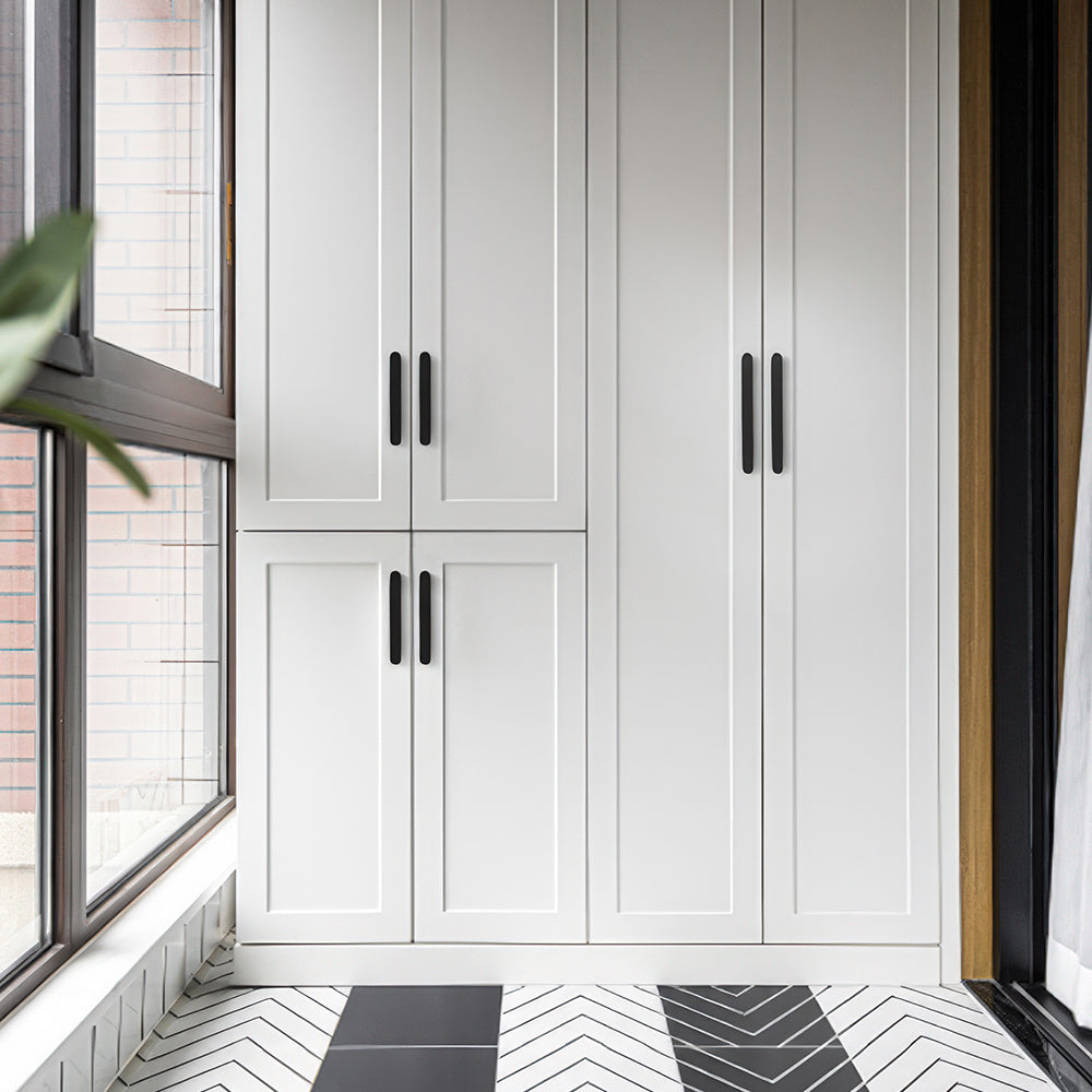 Black rounded-edge brass cabinet pull and round knob, pictured in one view installed on cabinetry in context