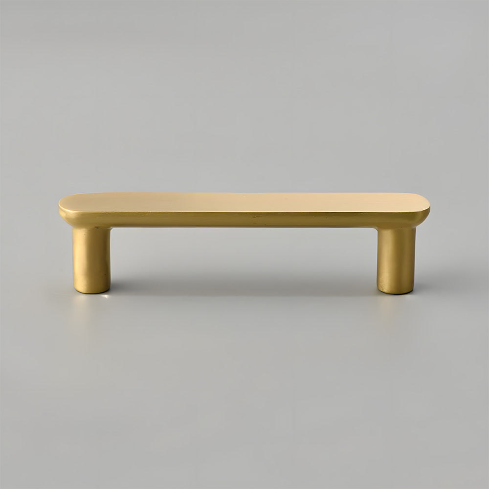Gold brass rounded bar cabinet pull, shown at close range on a clean neutral background