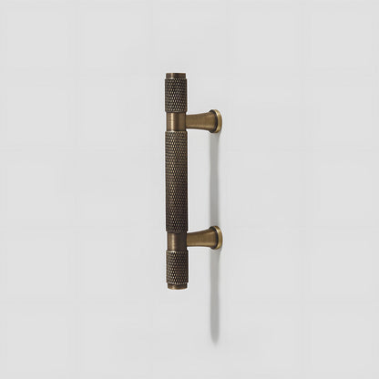 Antique bronze knurled brass T-bar cabinet pull, shown from one angle on a clean neutral background