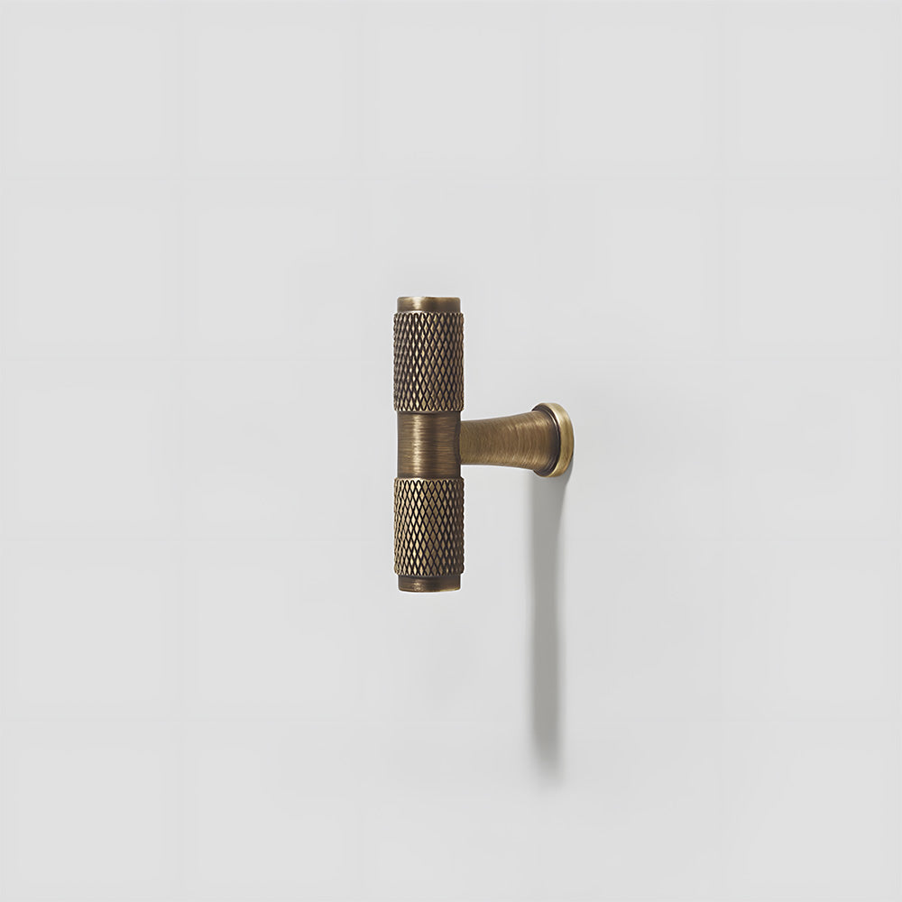 Antique bronze knurled brass T-bar cabinet pull, displayed from the side on a clean neutral background