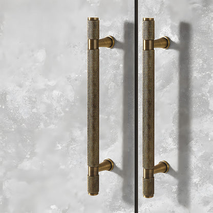 Antique bronze knurled brass T-bar cabinet pull, displayed from the side in an installed cabinet close-up