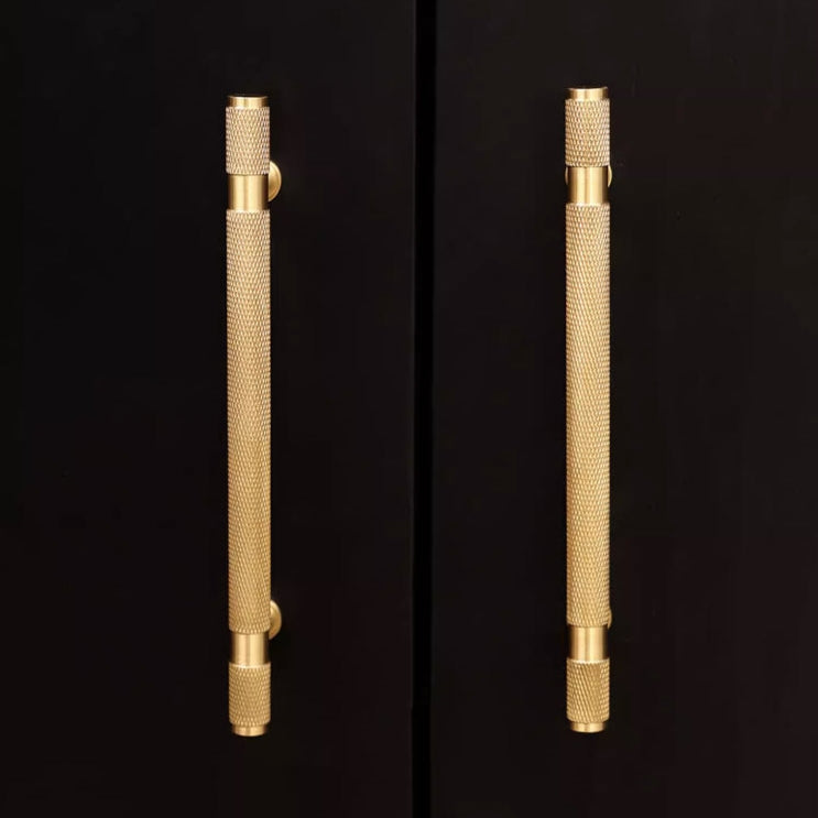 Gold knurled brass T-bar cabinet pull, presented for reference in an installed cabinet close-up