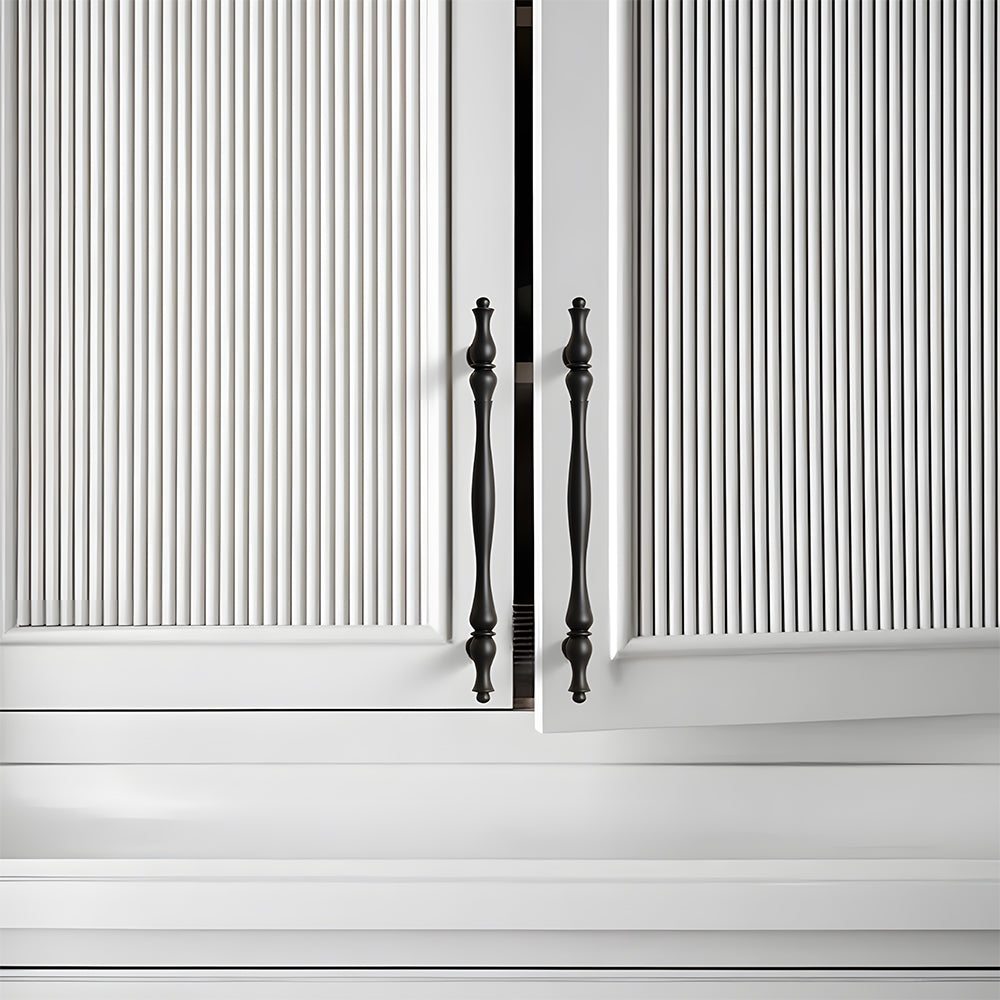 Black brass twisted cabinet pull and knobs, shown from one angle mounted on a finished cabinet front