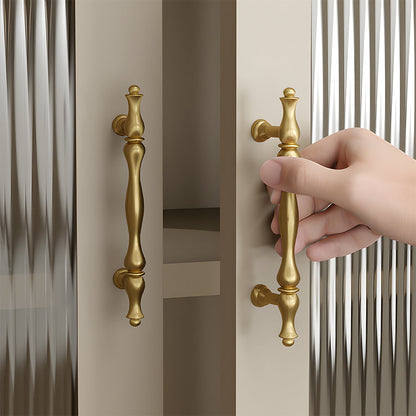 Brass twisted cabinet pull and knobs, shown clearly while held or operated by hand