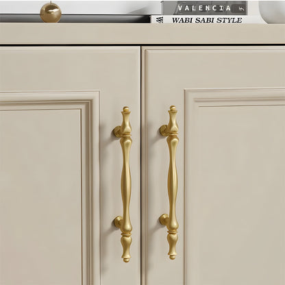 Gold brass twisted cabinet pull and knobs, shown from one angle installed on cabinetry in context