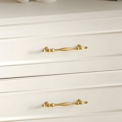 Gold brass twisted cabinet pull and knobs, pictured in one view installed on cabinetry in context