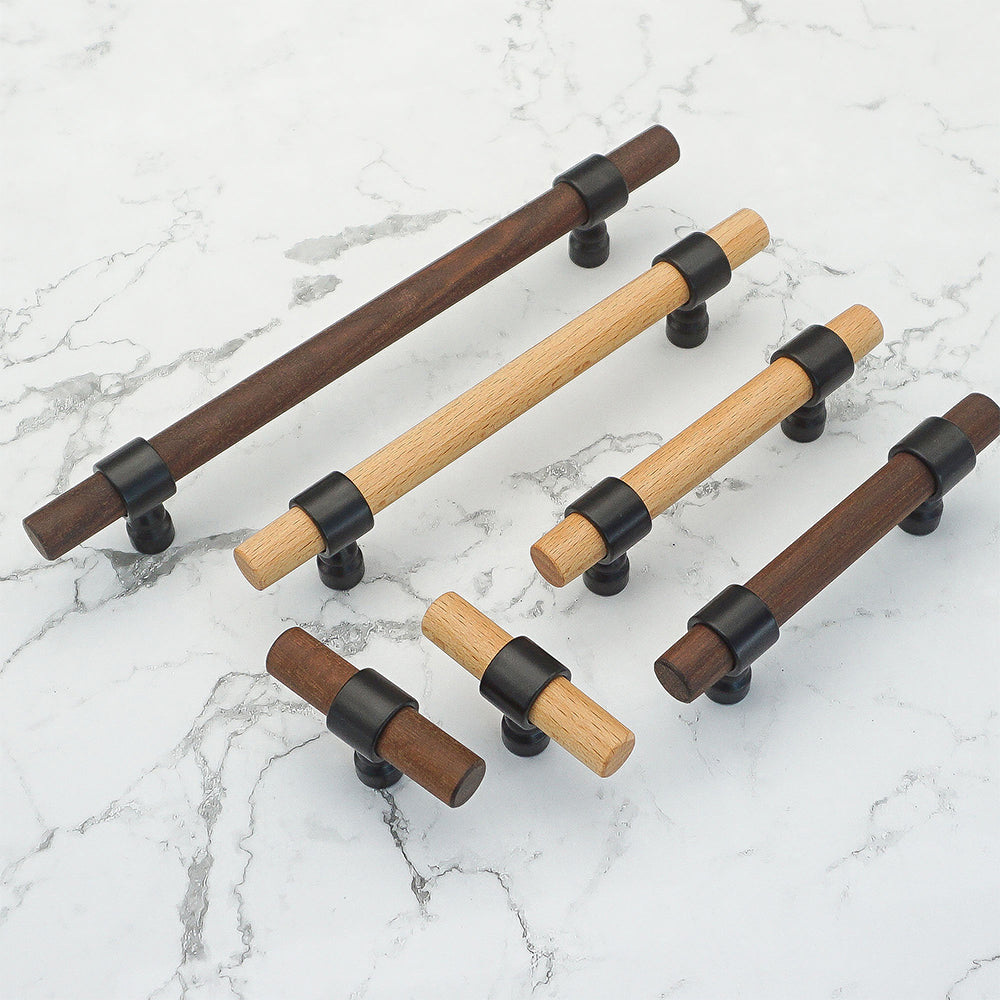 Walnut wood cabinet pull with round metal posts, grouped on a light surface to compare lengths and profiles