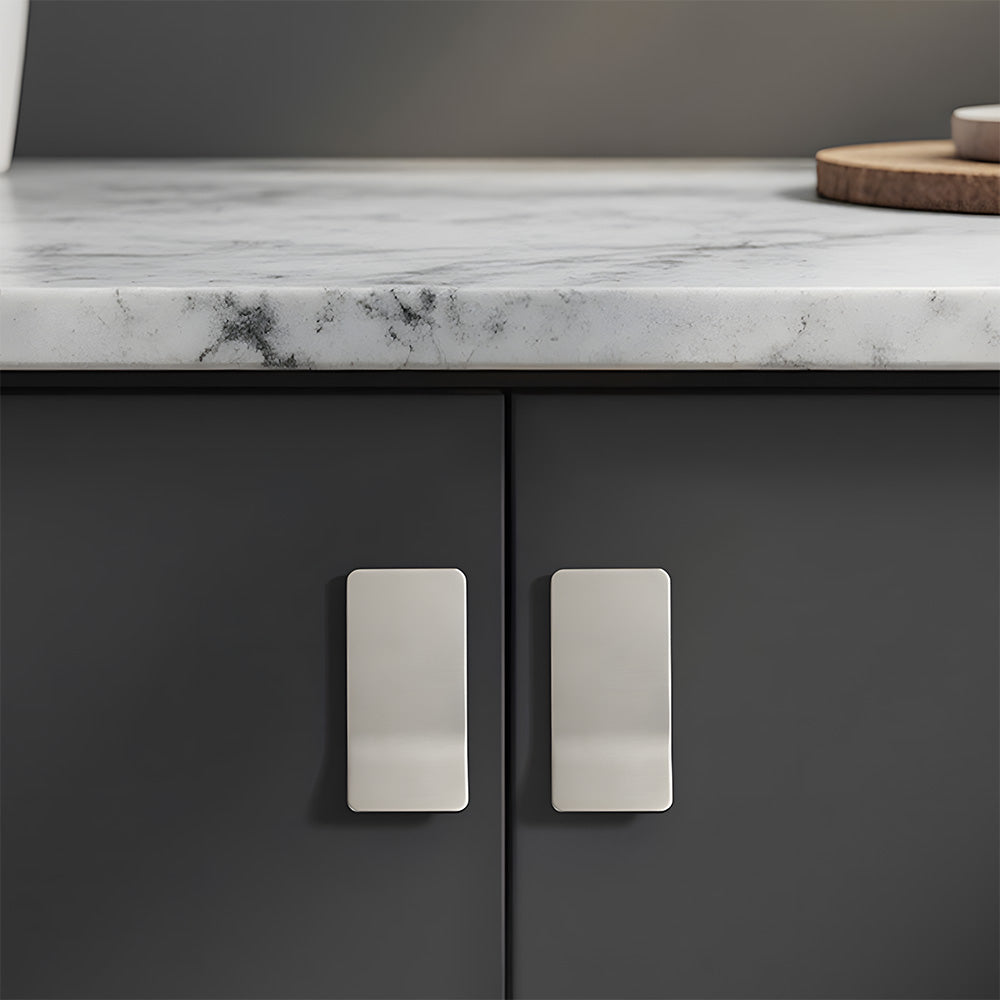 Silver square finger edge pull with a curved grip, shown at close range installed on cabinetry in context