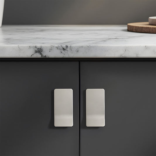 Silver square finger edge pull with a curved grip, shown at close range installed on cabinetry in context